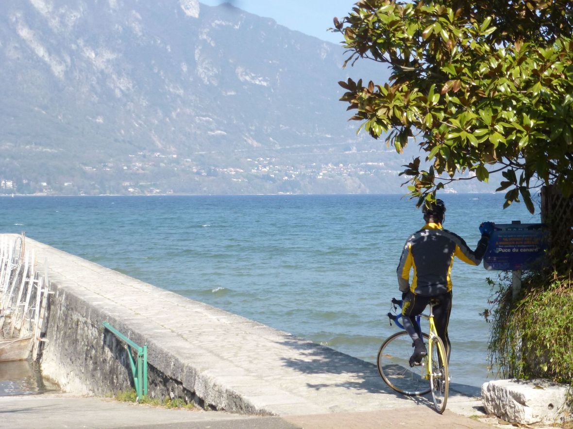 Cyclist in shade by water and mountain