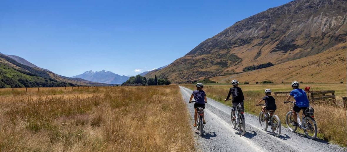 Four cyclists riding on gravel road in mountains