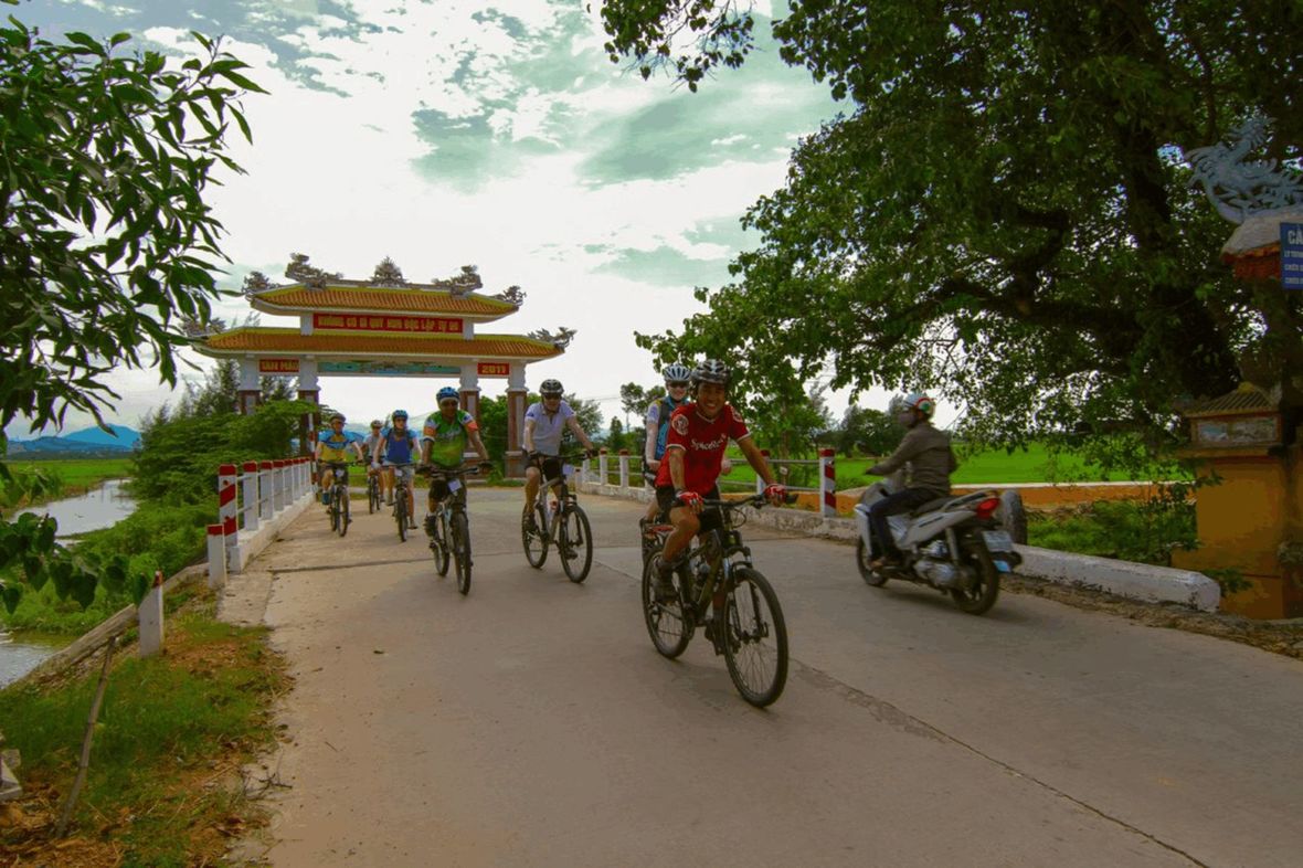 Cyclists riding on road with temple gate in background