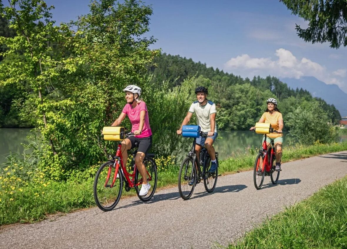 Three cyclists riding on paved path on sunny day
