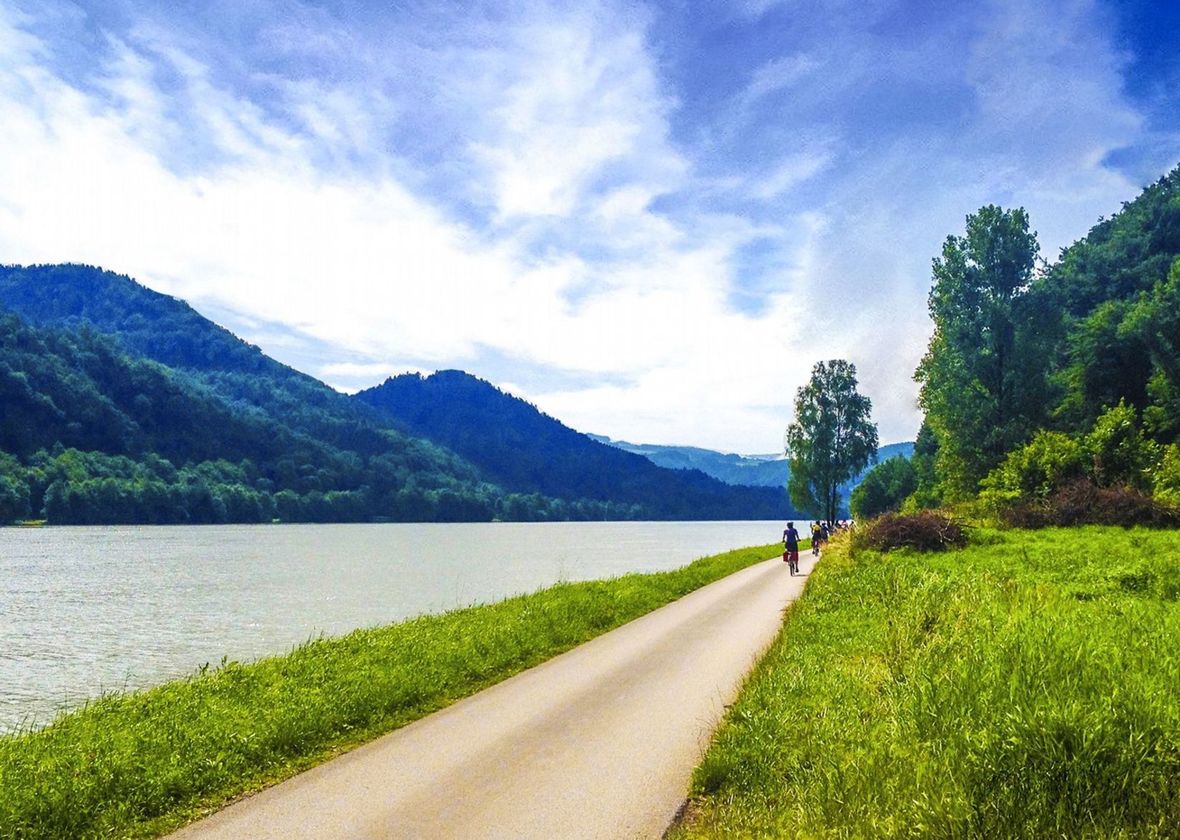Cyclists on a long flat path by a river