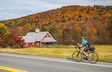 Cyclist passing by red barn