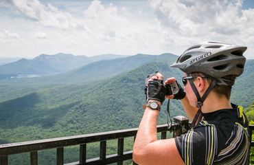 Cyclist taking photo at mountain viewpoint