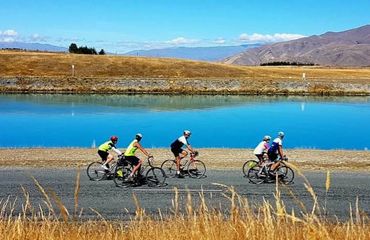 Cyclists riding past lake