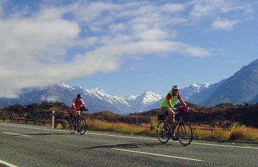 Road cyclists with moutains and clouds behind