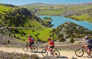 Cyclists riding on trail above lake
