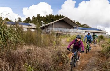Cyclists riding on trail with accommodation behind