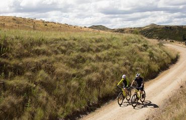 Cyclists on a gravel trail surrounded by hills