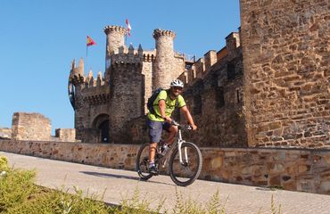 Cyclist on paved trail passing castle