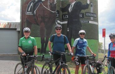 Cyclists standing infront of painted silos