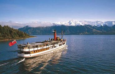 Steamship sailing across lake with mountains in background