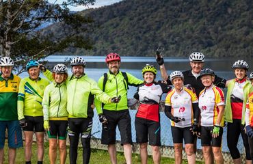 Group of cyclists standing by water for photo