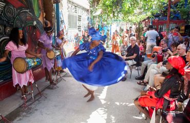 Woman dancing in blue dress with onlookers