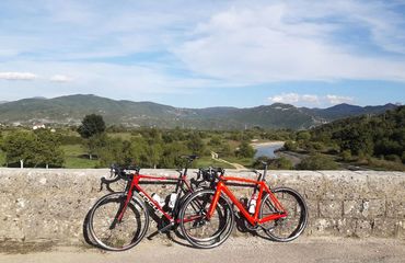 Two bikes resting on a stone bridge overlooking countryside