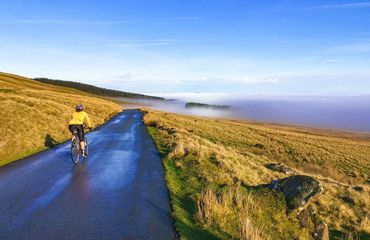 Lone cycling on remote road above the mist