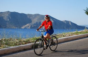 Happy cyclist riding past ocean and mountain