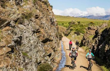 Cyclists riding through rocky hills on trail