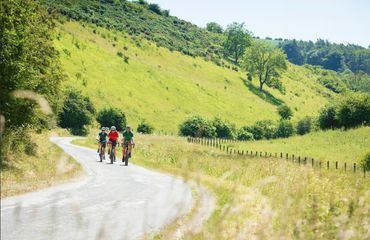 Cyclists riding on rural road with hill on one side