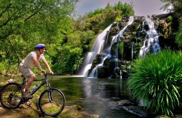 Cyclist in front of a waterfall