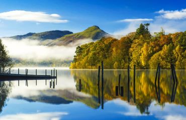 Low cloud on a lake with trees and mountains around