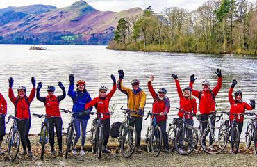 Group of cyclists in front of lake waving