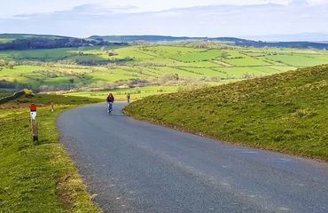 Cyclist riding up hilly road