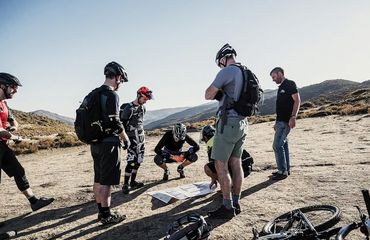 Group of cyclists off the bikes on rocky plateau, looking at map