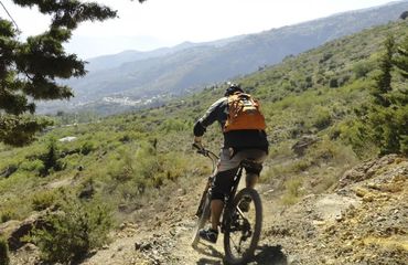 Mountain biker cycling on rural track with mountains in distance