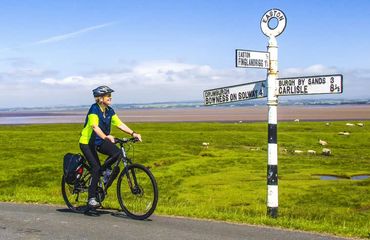 Cyclist looking at signpost