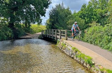 Cyclist riding on pathway next to stream