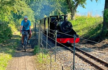 Cyclist riding alongside small steam train