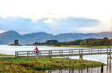 Cyclist riding over a small bridge over water