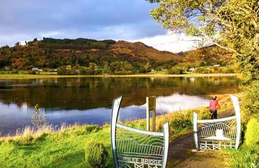 Cyclist riding through gateway to trail by loch