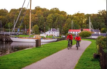 Cyclists riding past sail boats