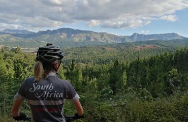 Woman in cycling gear looking out over mountains