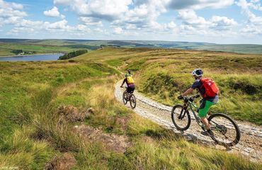 Cyclists riding on rural trail with lake in distance