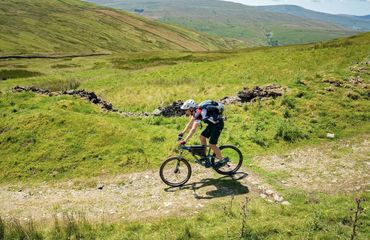 Cyclist on trail with hills in background