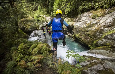 Person in helmet and wetsuit jumping into waterfall