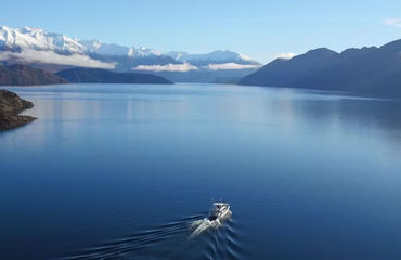 Boat on vast lake with mountains in distance