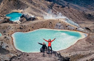 Two people waving at crater lake