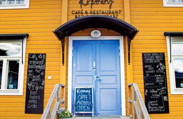 Yellow building with blue door and blackboards outside