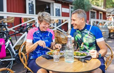 Couple in lycra sitting at outdoor cafe eating