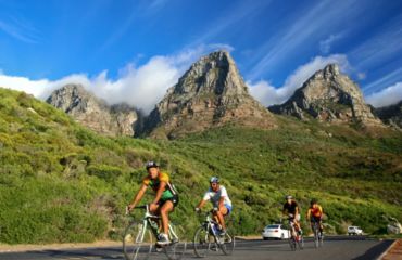 Riders on road with peaked mountains behind