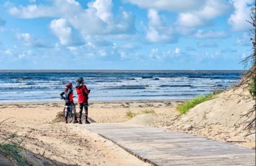 Couple of cyclists on sandy beach