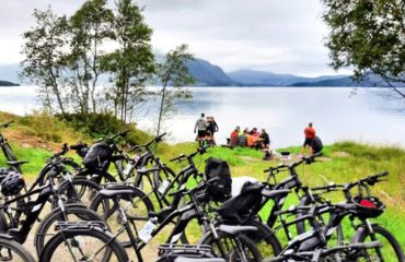 Cyclists sitting by lake with their bikes in the foreground