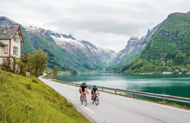 Cyclists riding alongside mountain fjord