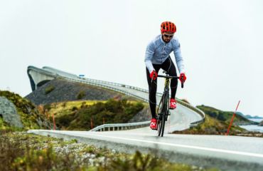 Cyclist on road with curved bridge behind