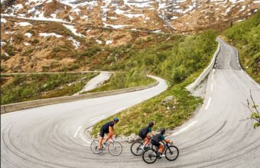 Three cyclists on hairpin bed on mountain road