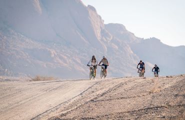 Cyclists riding down barren desert-like hill