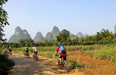 cyclists riding along path with karsts in distance
